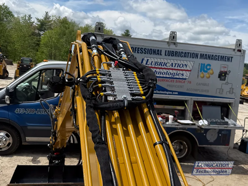 Feed and tail lines from a ReliaMAX™ automatic lubrication system routed along the boom of a CAT 305 Mini Excavator