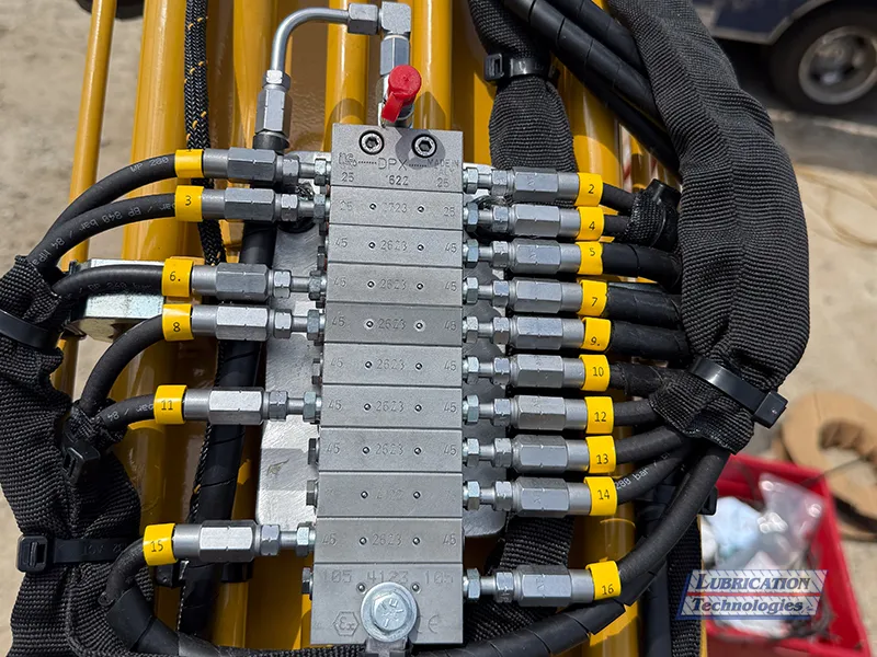 ReliaMAX™ lubrication system divider valve on a CAT 305 Mini Excavator, showing feed line and multiple numbered tail lines