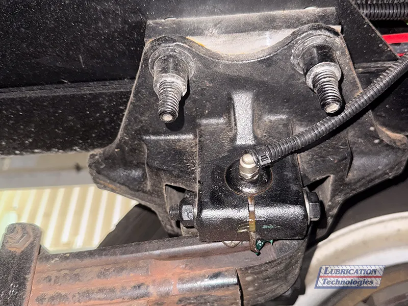 Grease fitting installed on suspension component with lubrication line attached.